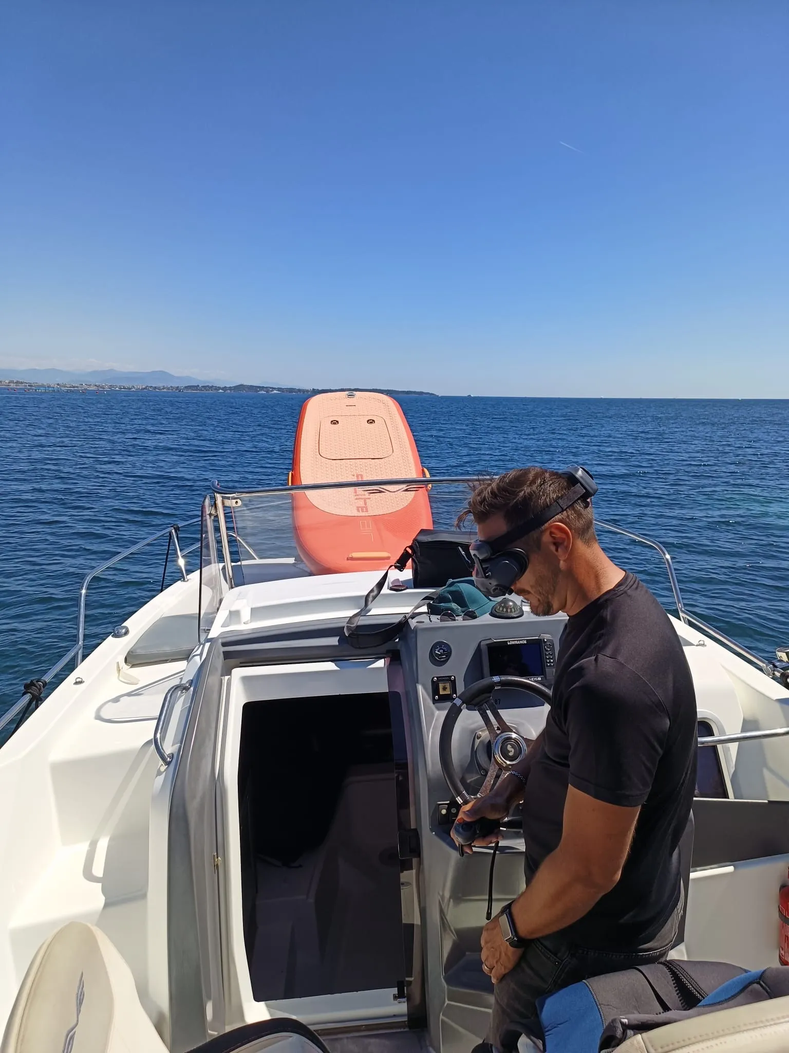 À la barre du bateau, la planche eFoil à bord
